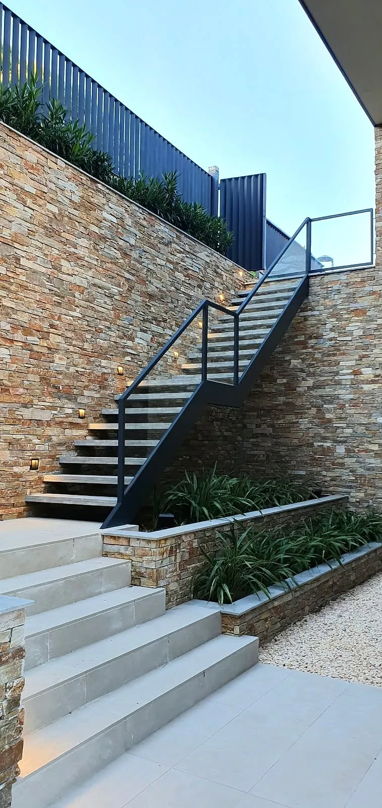 Escalera exterior con barandilla metálica y aplacado de piedra