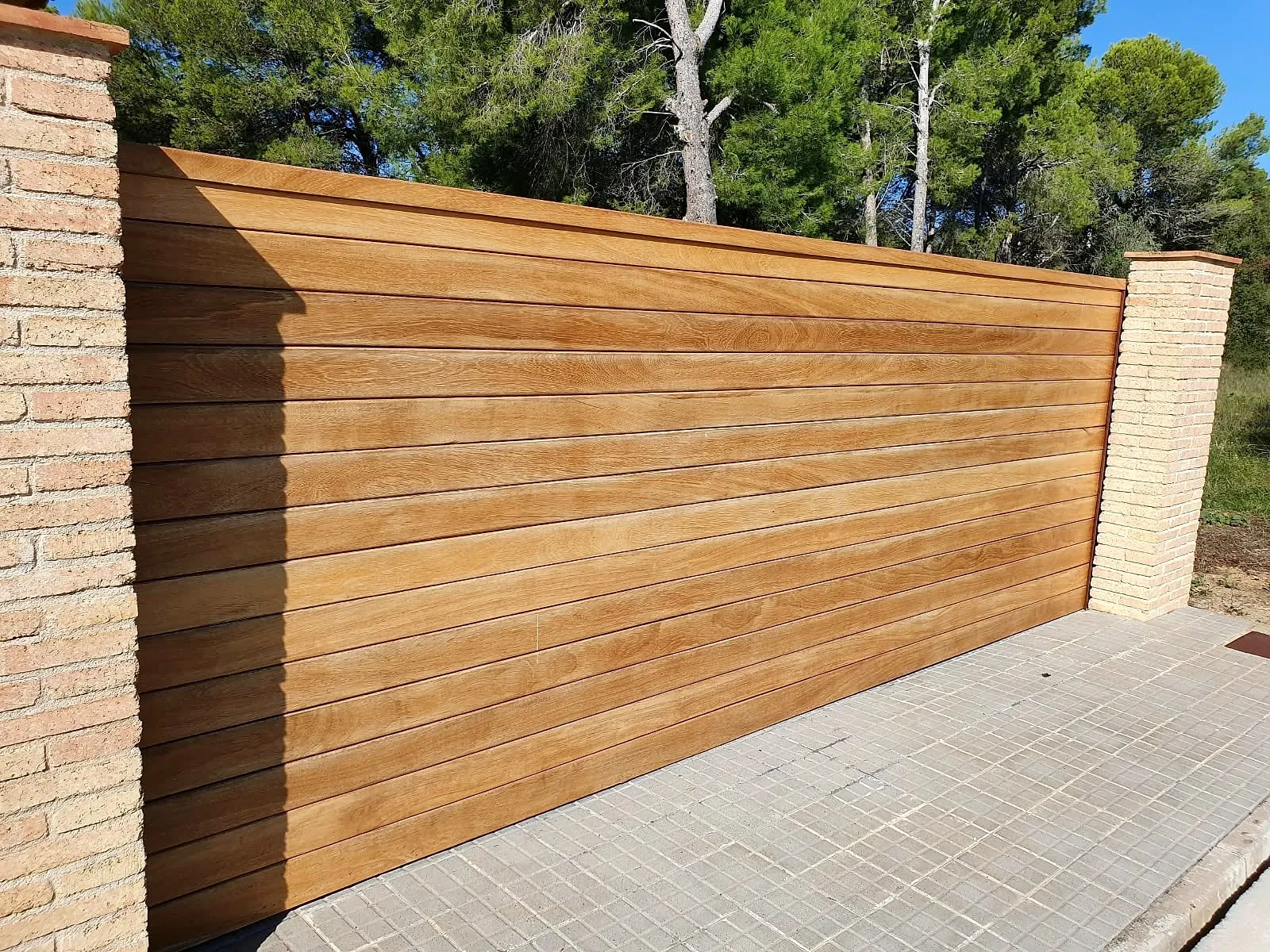 Valla de listones de madera tratada entre pilares de ladrillo