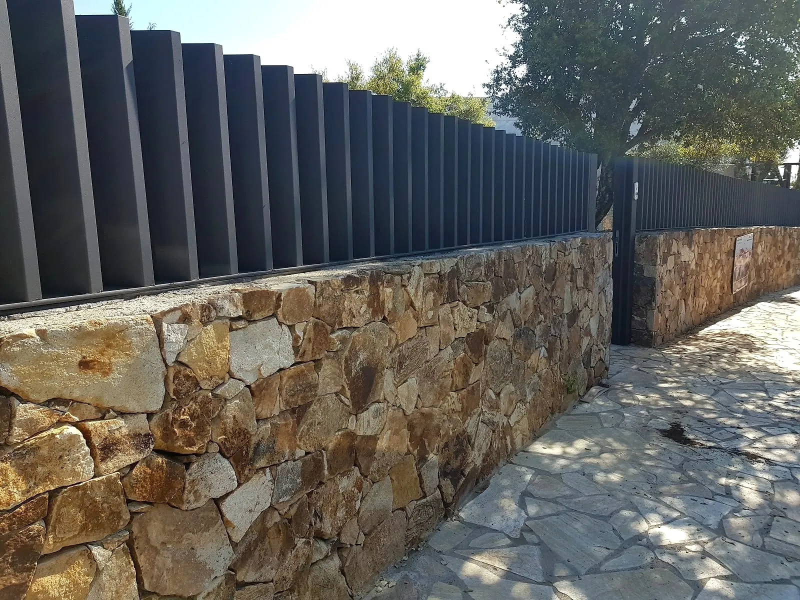 Valla de lamas lacada en antracita sobre muro de piedra